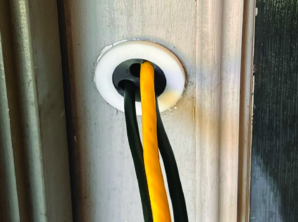 Prototype StormPlug installed with cords routed through a closed exterior door